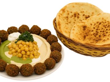 Classic hummus bowl topped with chickpeas, 12 falafel balls, tahini, herbs, and warm pita bread