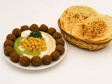 Hummus bowl topped with chickpeas, falafel balls, herbs, and pita bread – a perfect vegan delight