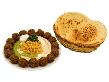 Hummus bowl topped with chickpeas, falafel balls, herbs, and pita bread – a perfect vegan delight