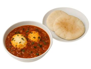Authentic shakshuka with poached eggs in rich tomato sauce, served with fresh pita.