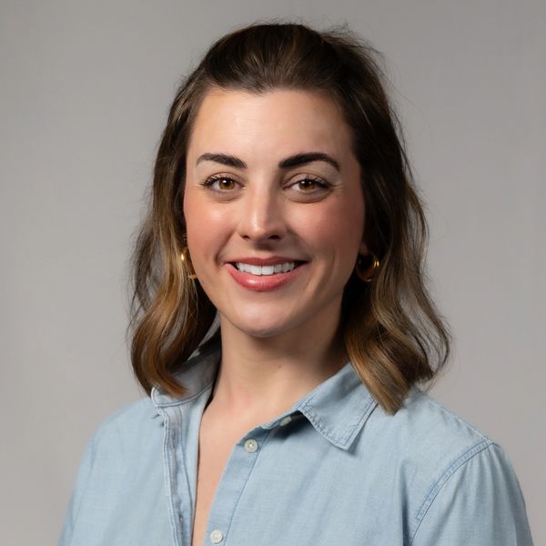 Smiling woman with shoulder-length hair in a light blue shirt.