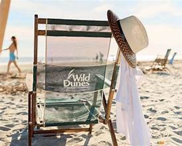 Beach chair with a hat and shirt on the sand.