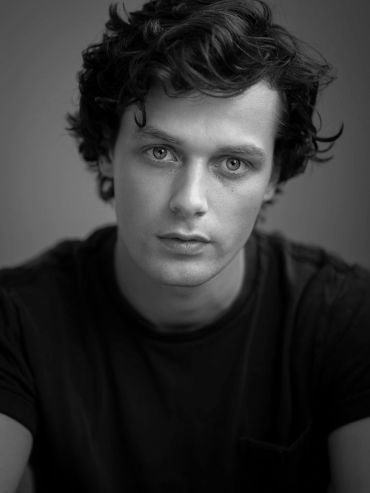 Black and white portrait of a young man with curly hair.