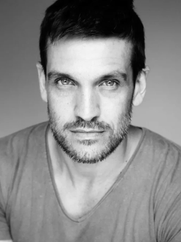 Black and white portrait of a man with light eyes and a beard.