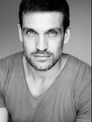 Black and white portrait of a man with light eyes and a beard.