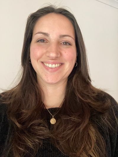 Smiling woman with long brown hair and gold pendant.