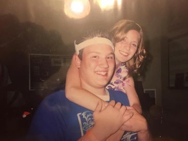 A young man giving a piggyback ride to a smiling girl indoors.