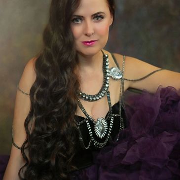Woman with long curly hair and ornate jewelry.