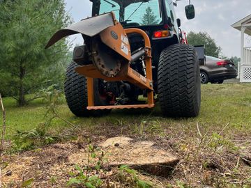 A stump grinder attached to a tractor for removing tree stumps.