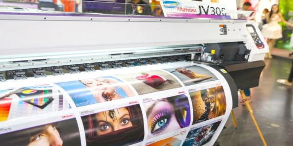 Large printer producing vibrant photo prints with various colorful images.