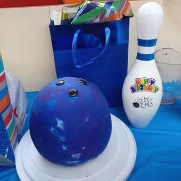 Bowling-themed birthday cake and decorations on a table.