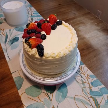 A white frosted cake decorated with fresh strawberries, raspberries, and blackberries.