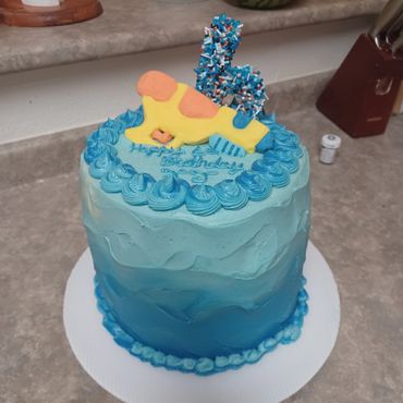 Blue ombre birthday cake with a water gun and number 6 decoration.