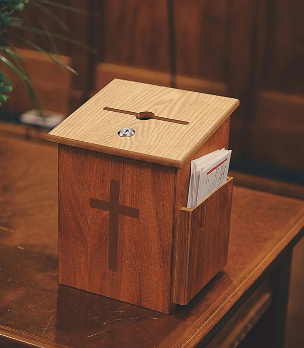 Wooden donation box with a cross and envelopes on the side.