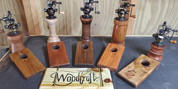 Handcrafted wooden pepper mills with matching wooden bases on display.