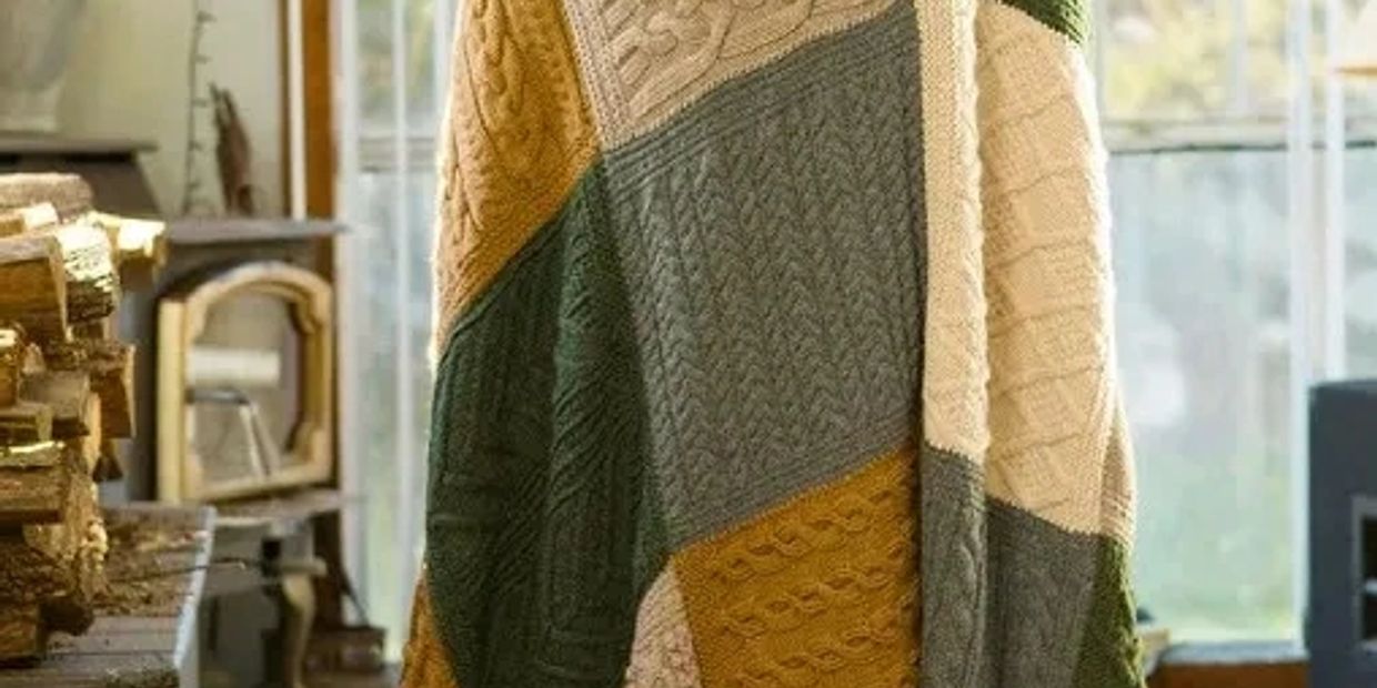 Patchwork knitted blanket draped in a cozy room with firewood.
