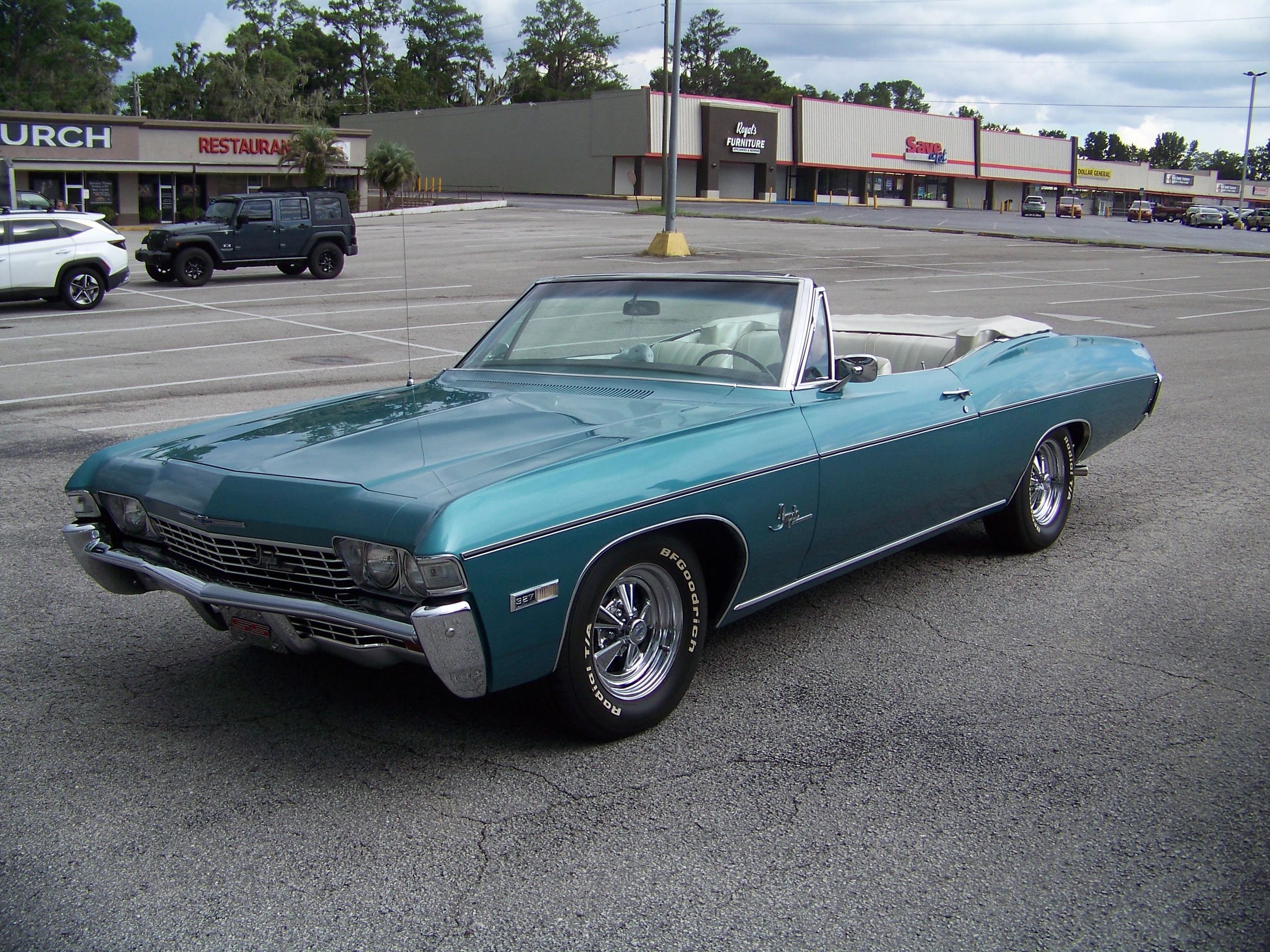 Blue vintage convertible car in a parking lot.