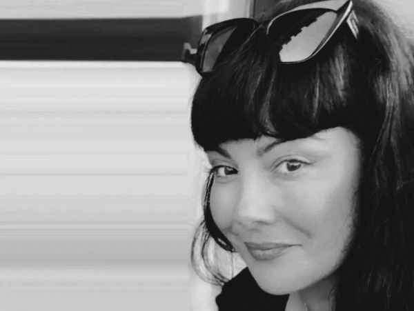 Black and white portrait of a woman with sunglasses on her head.