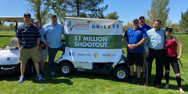 Group standing next to golf cart with $1 Million Shootout banner.