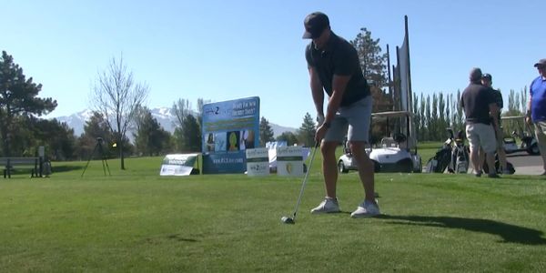 Man preparing to putt on a sunny golf course with others in the background.