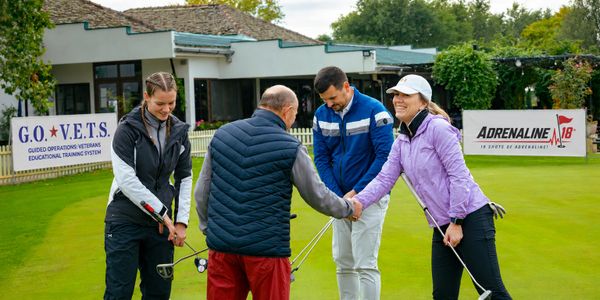 Four people enjoying a friendly golf game on a green putting area.