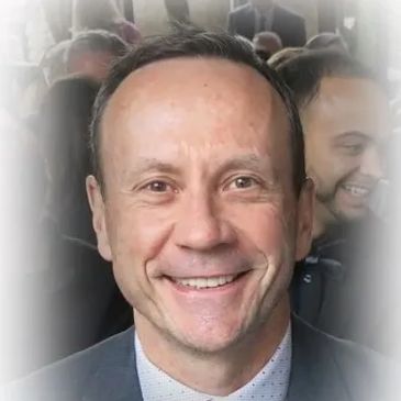 A smiling man in a suit at a formal event.