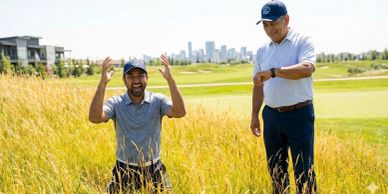 A man joyfully celebrates while another man checks his watch on a golf course.