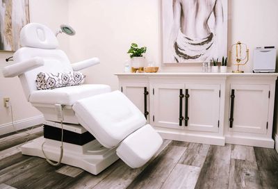 A clean, modern treatment room with a white reclining chair and stylish decor.