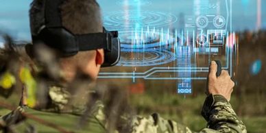 Soldier using augmented reality headset with digital interface outdoors.