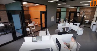 Modern office space with partitioned work desks and glass-walled rooms.