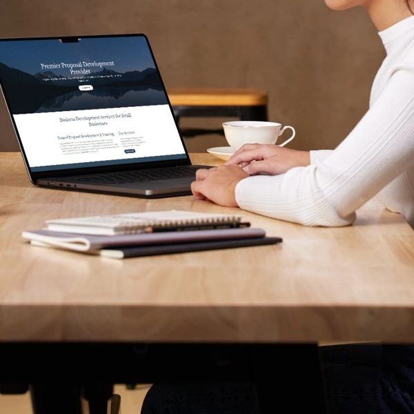 person at a table typing on a laptop with website on screen