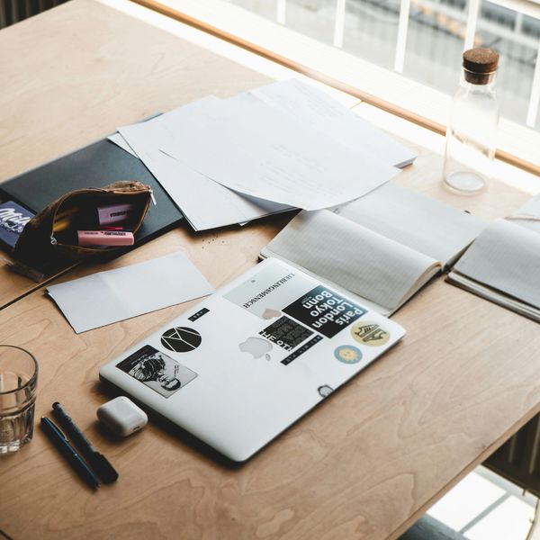 A tidy workspace with a laptop, notebooks, pens, and papers on a wooden desk.