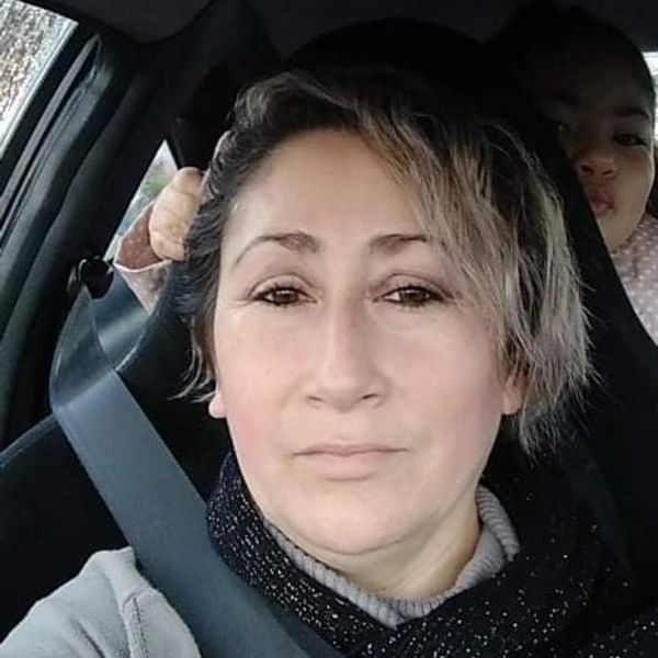 Woman wearing a seatbelt inside a car with a child in the backseat.