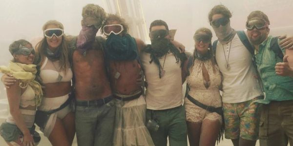 Group wearing goggles and scarves in a dusty environment, posing together.