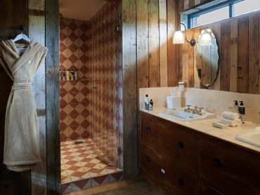 Cozy rustic bathroom with wooden walls and tiled shower area.