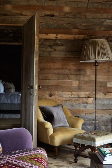 Cozy rustic living room with wooden walls and vintage furniture.