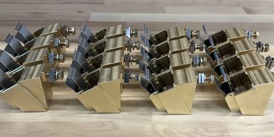 Four identical metal bracket assemblies with bolts on a wooden surface.