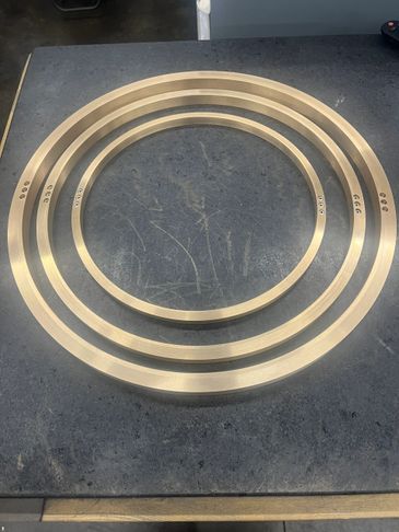 Three brass rings of different sizes placed on a dark surface.