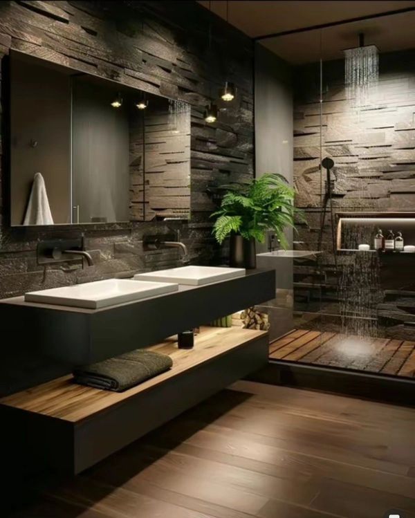 Modern bathroom with dark stone walls, dual sinks, and a glass-enclosed shower.