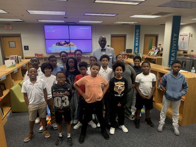 A group of children and an adult posing in a library.