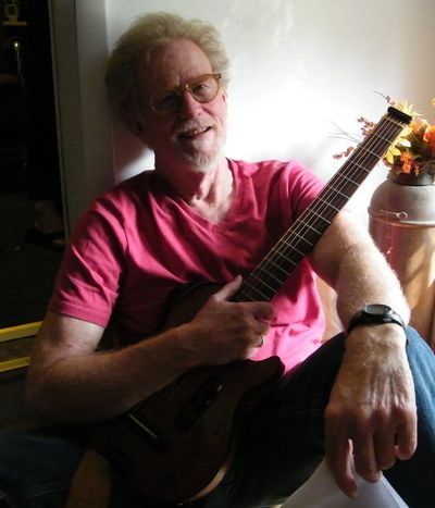 A man wearing a pink shirt and holding a guitar