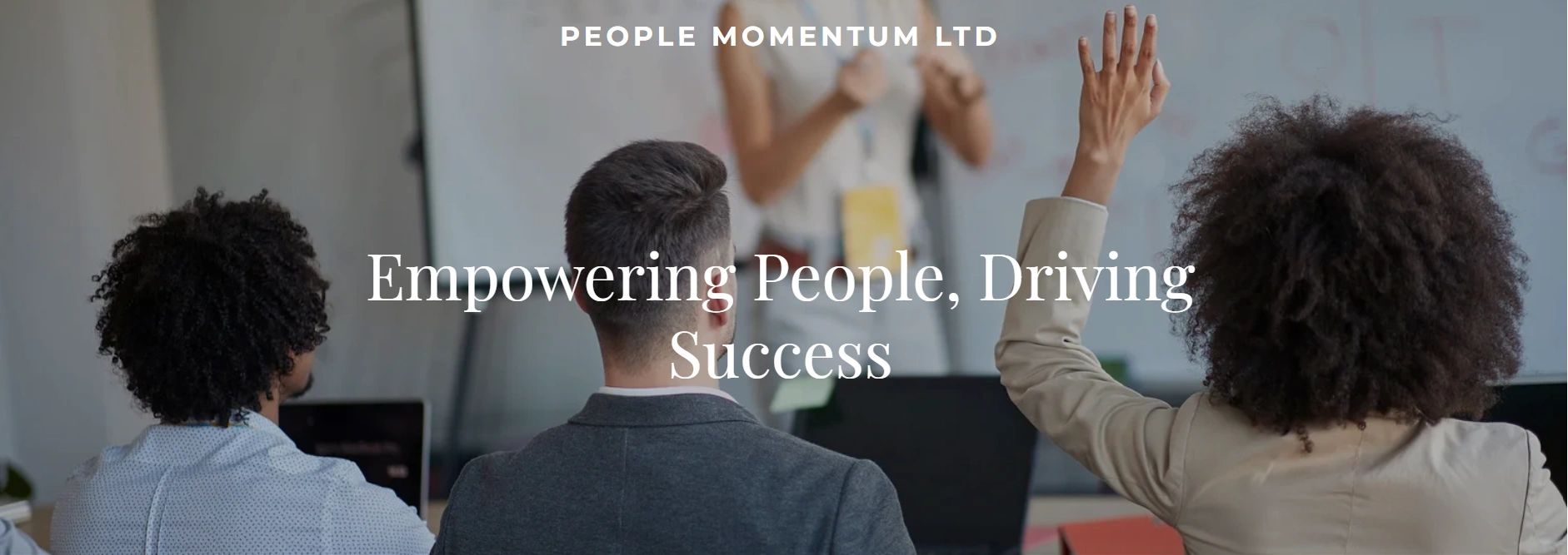 People attending a seminar, one raising hand to participate.