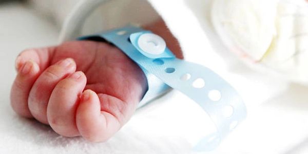 main de bébé avec un bracelet de naissance bleu