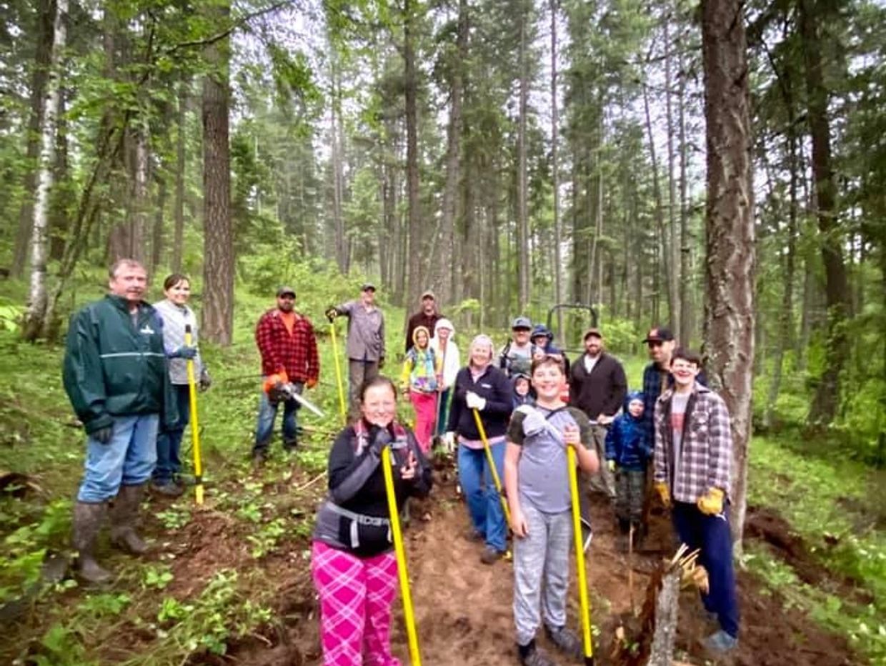 Group of people volunteering for forest trail maintenance in a wooded area.