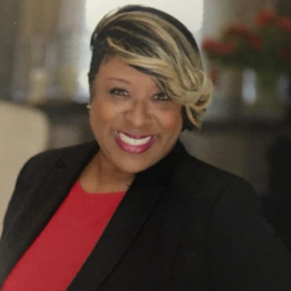 Woman smiling wearing a black jacket and red top.