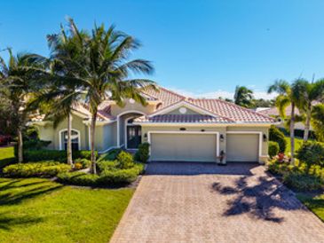 A sunny suburban house with palm trees and a three-car garage.