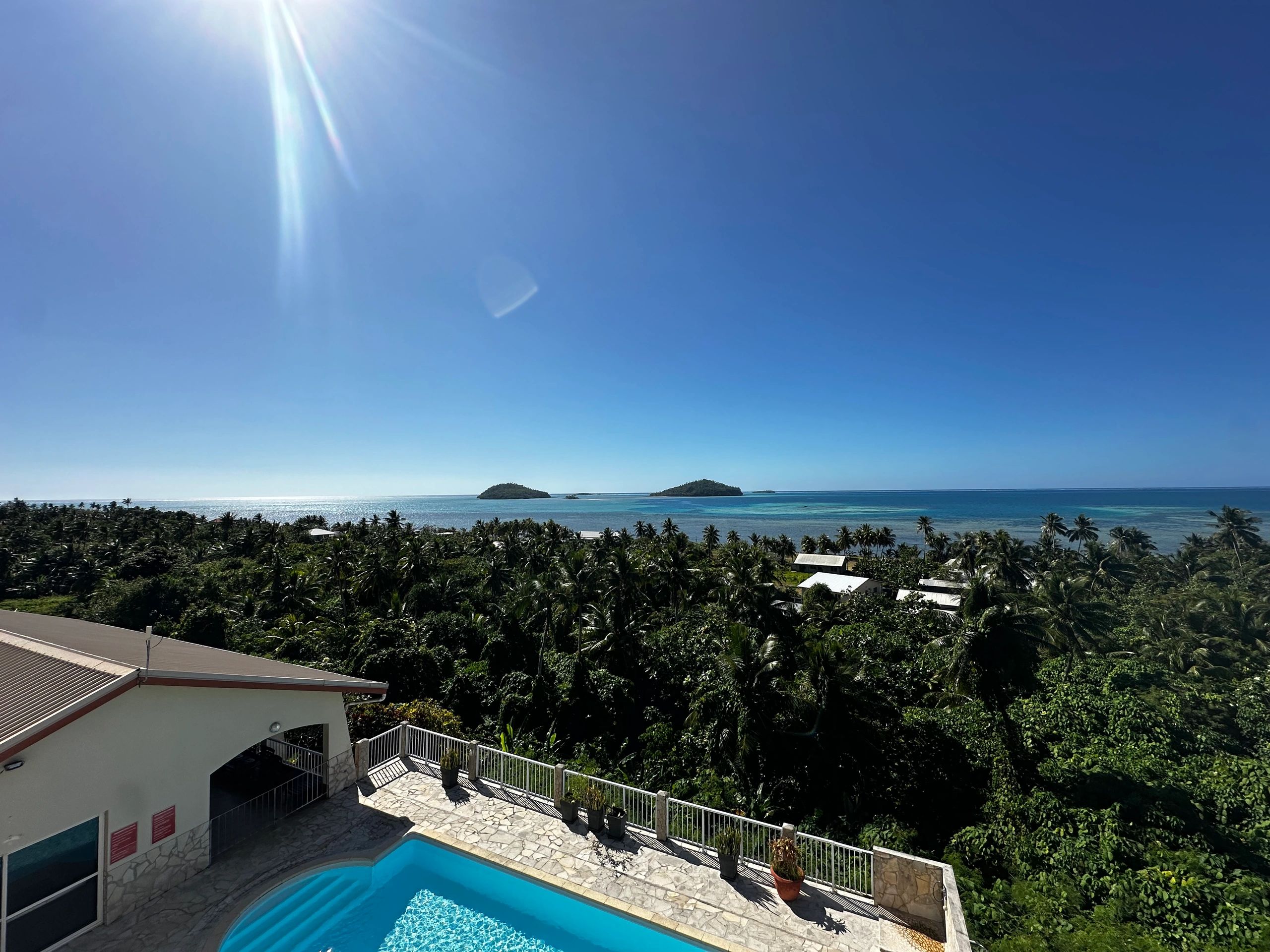 Sunny tropical coastline with a pool and ocean view.