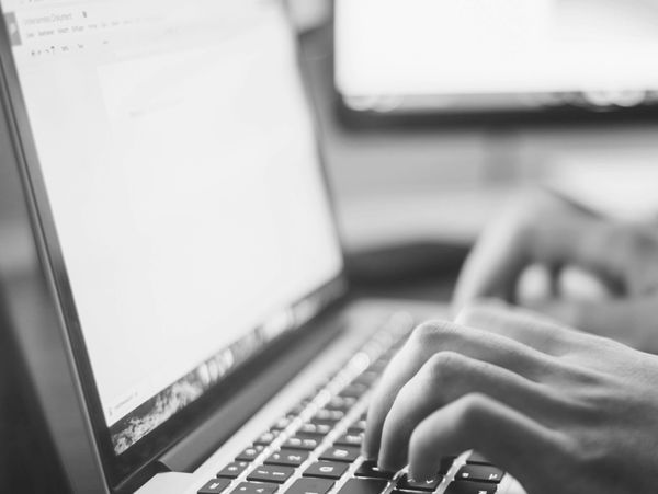 Black and white photo of hands typing on a laptop keyboard.