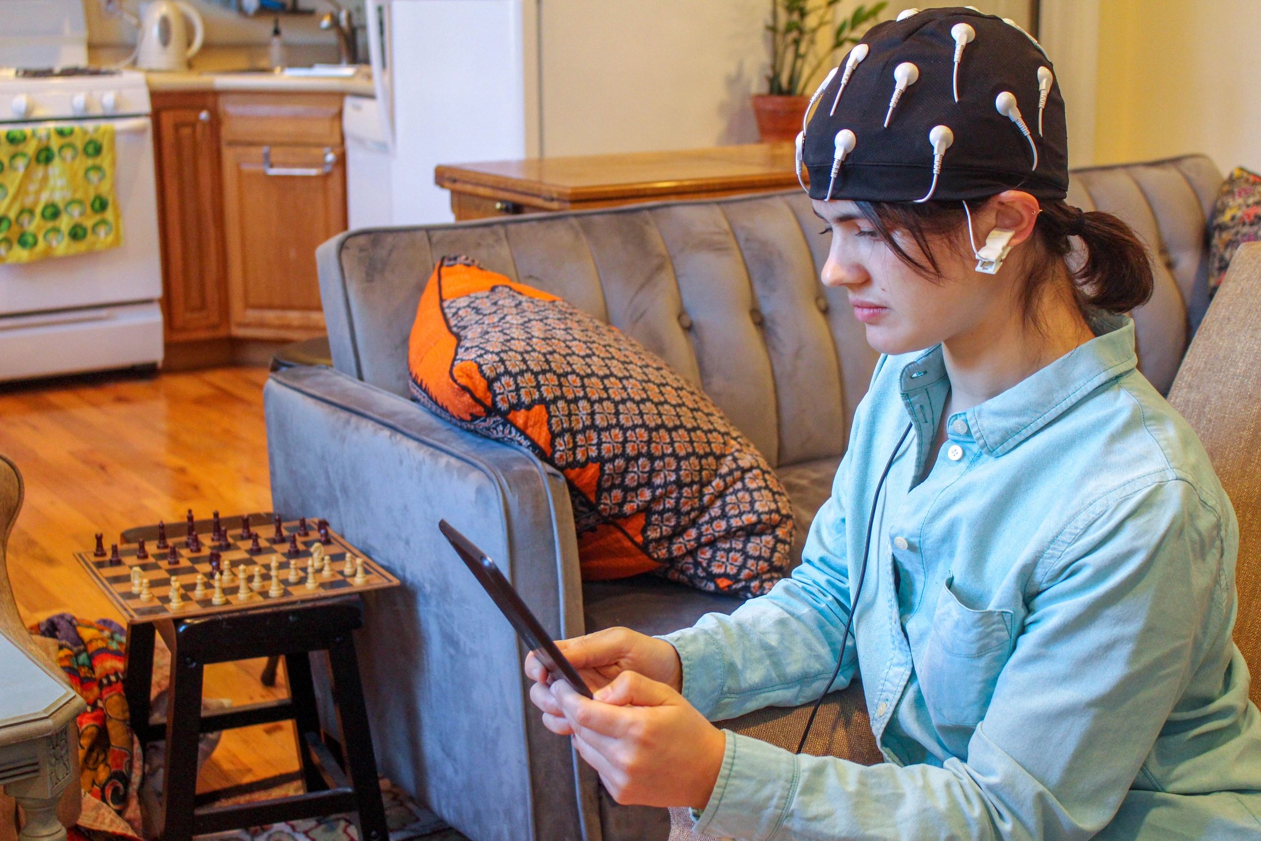 A person wearing an EEG cap using a tablet in a living room.