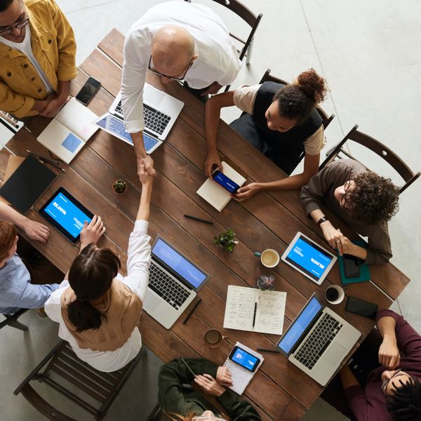 Team of diverse professionals collaborating around a table with laptops and tablets.